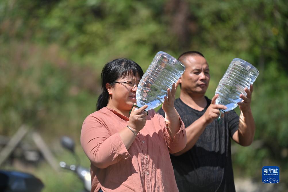 楊寧（左）在查看村民剛剛采集的水樣，為山泉水引水工程做準(zhǔn)備（10月8日攝）。新華社記者 黃孝邦 攝